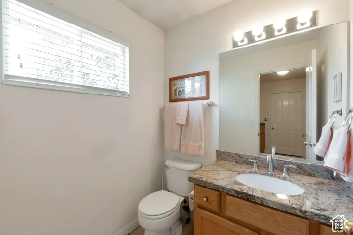 Bathroom featuring a light wood-finish vanity with an oval undermount sink, a polished chrome faucet, and a speckled stone countertop