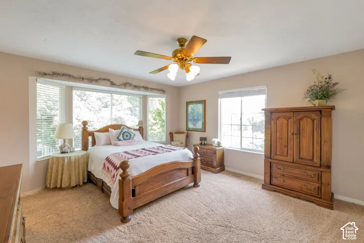 Spacious room featuring a bay window with ample natural light, a ceiling fan with integrated lighting, and neutral wall tones