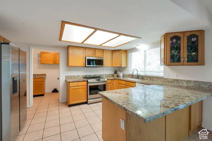 Kitchen featuring light wood cabinetry with display uppers, granite-look countertops, and an island with breakfast bar seating