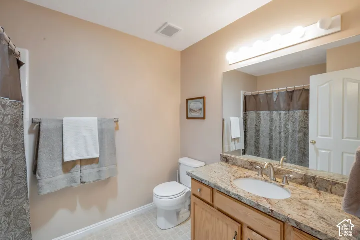Bathroom featuring a single vanity with stone-finish countertop, undermount sink, and brushed nickel faucet