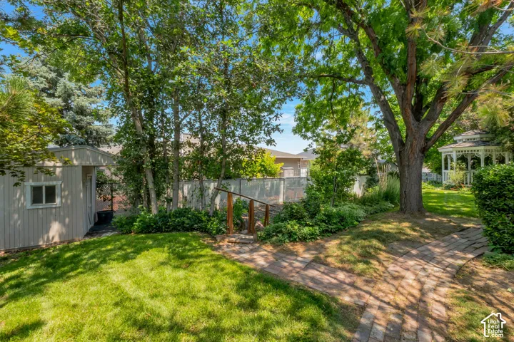 Expansive backyard with a manicured lawn, mature trees, and a brick pathway