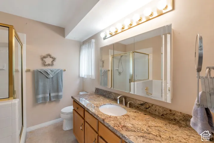 Bathroom featuring a spacious vanity with a granite-style countertop, dual sinks, and light wood cabinetry