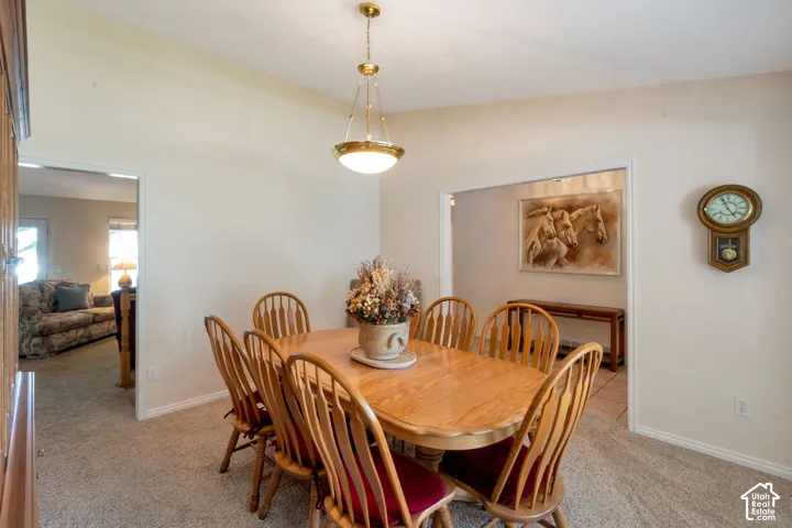 Dining area featuring a brass-finish ceiling light fixture, neutral-toned walls, and carpet flooring