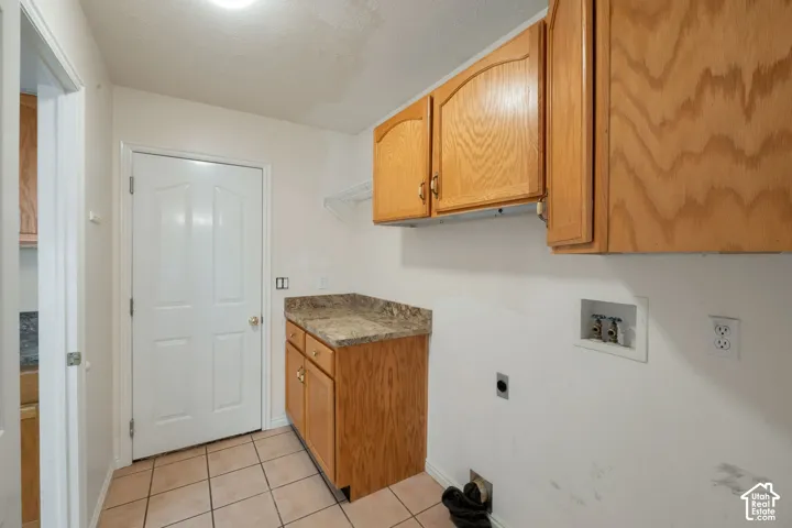 Utility room with built-in cabinetry, durable tile flooring, and a speckled countertop