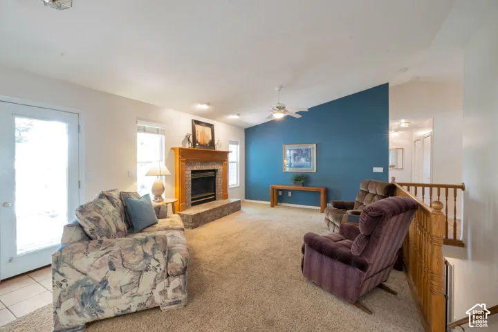 Carpeted living area featuring a fireplace with a wood mantle and brick surround