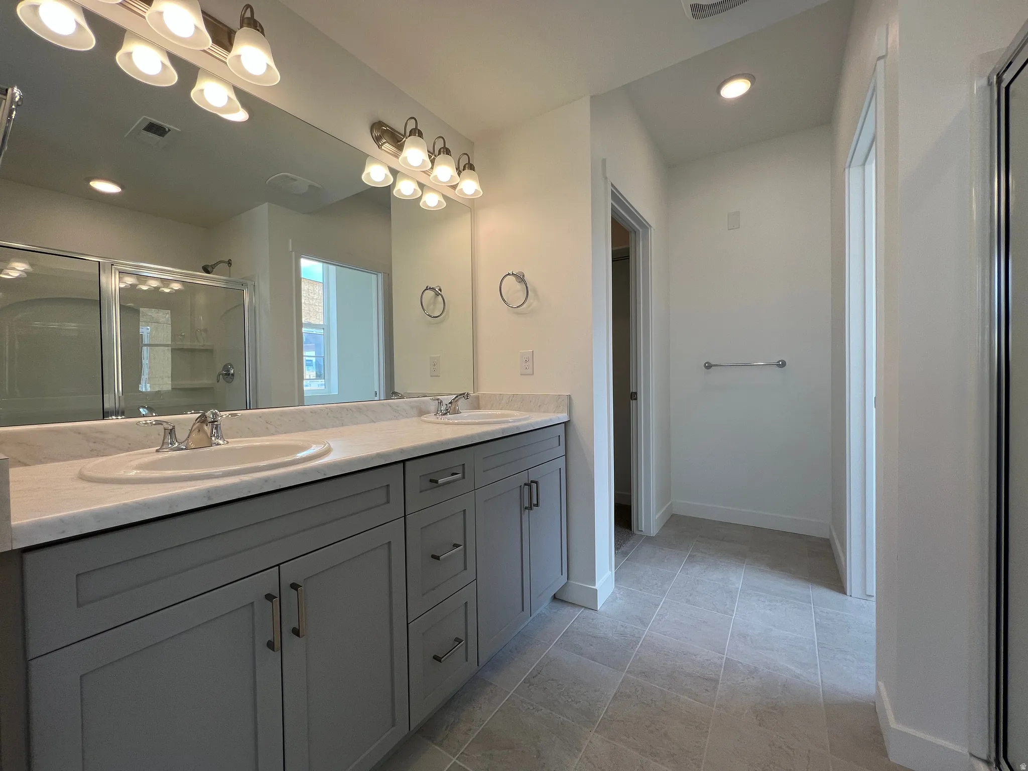 Dual vanity with light gray cabinetry and white countertops