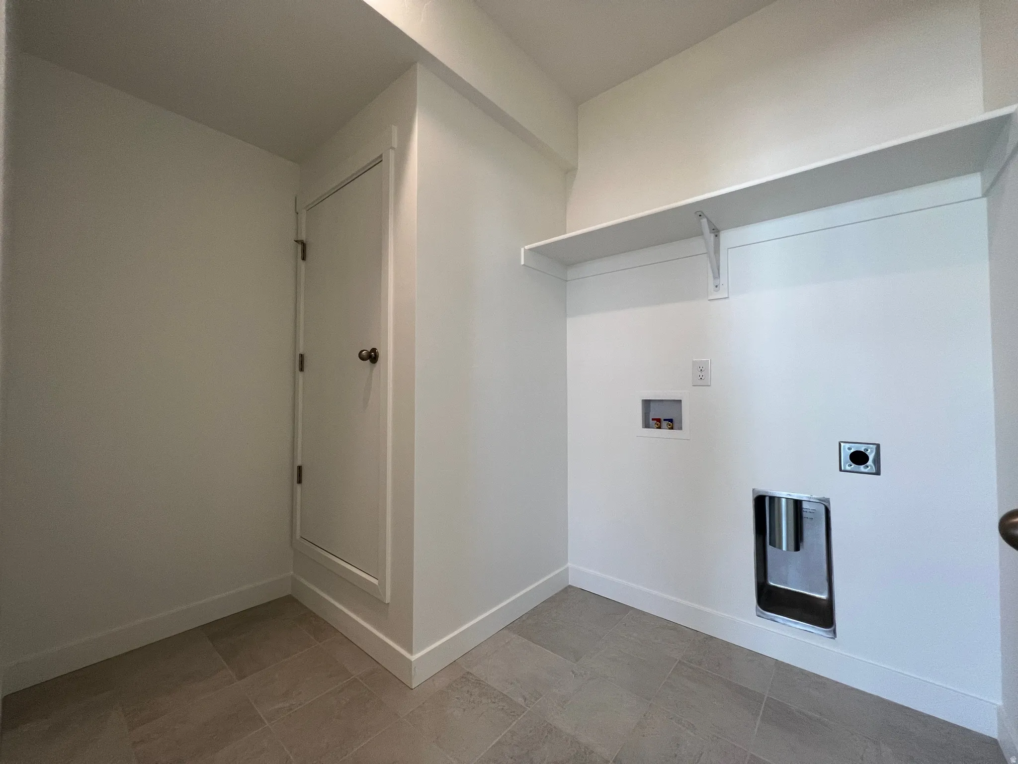 Laundry area featuring tile flooring, a built-in storage shelf, and utility hookups