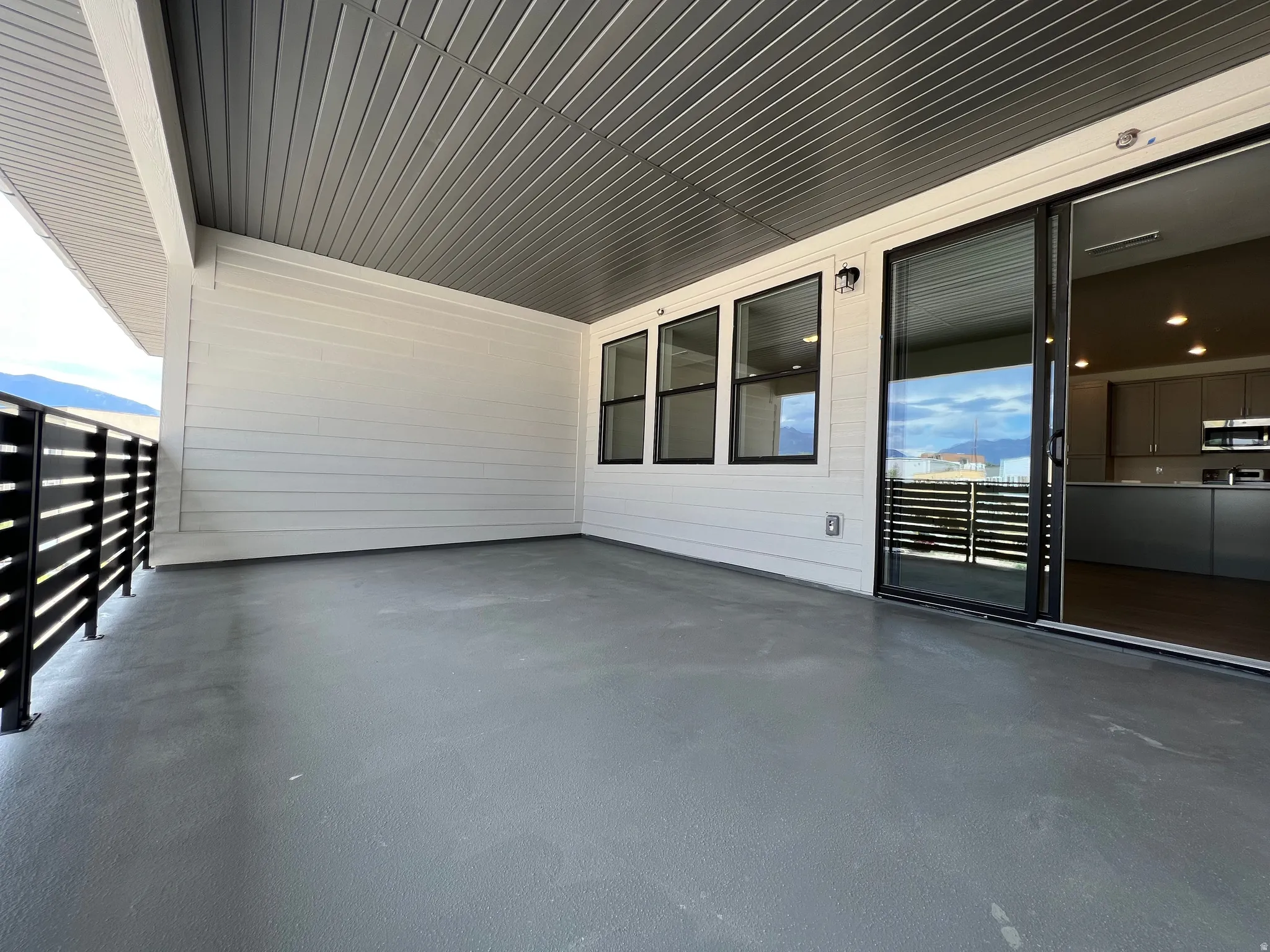 Spacious outdoor patio featuring a gray finished floor and a slatted black railing