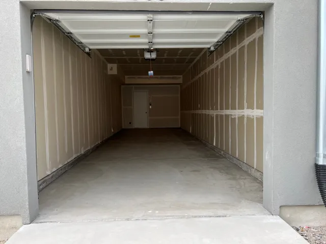 Spacious garage with concrete flooring, unfinished drywall, and an overhead garage door opener