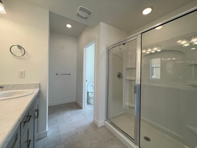 Bathroom featuring a single vanity with stone-finish countertop, undermount sink, and dark cabinetry with modern hardware