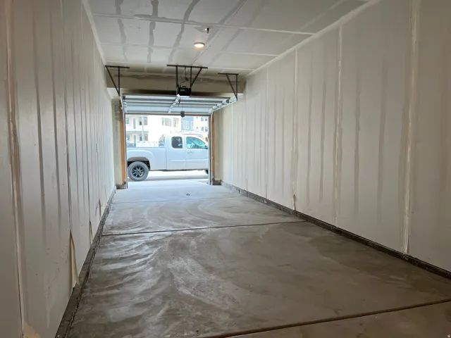 Single-car garage with a concrete floor, unfinished drywall walls, and an overhead garage door