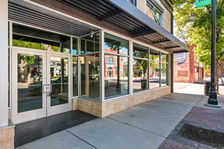 Contemporary storefront featuring expansive glass panels, a corrugated metal awning, and a stacked stone base