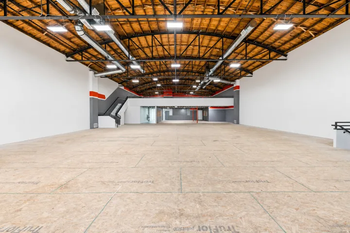 Expansive open-plan interior featuring exposed wood-beam ceilings and visible ductwork
