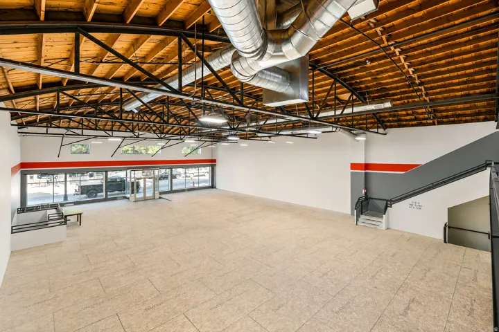 Spacious open-concept interior featuring exposed wood-beam ceilings and visible ductwork
