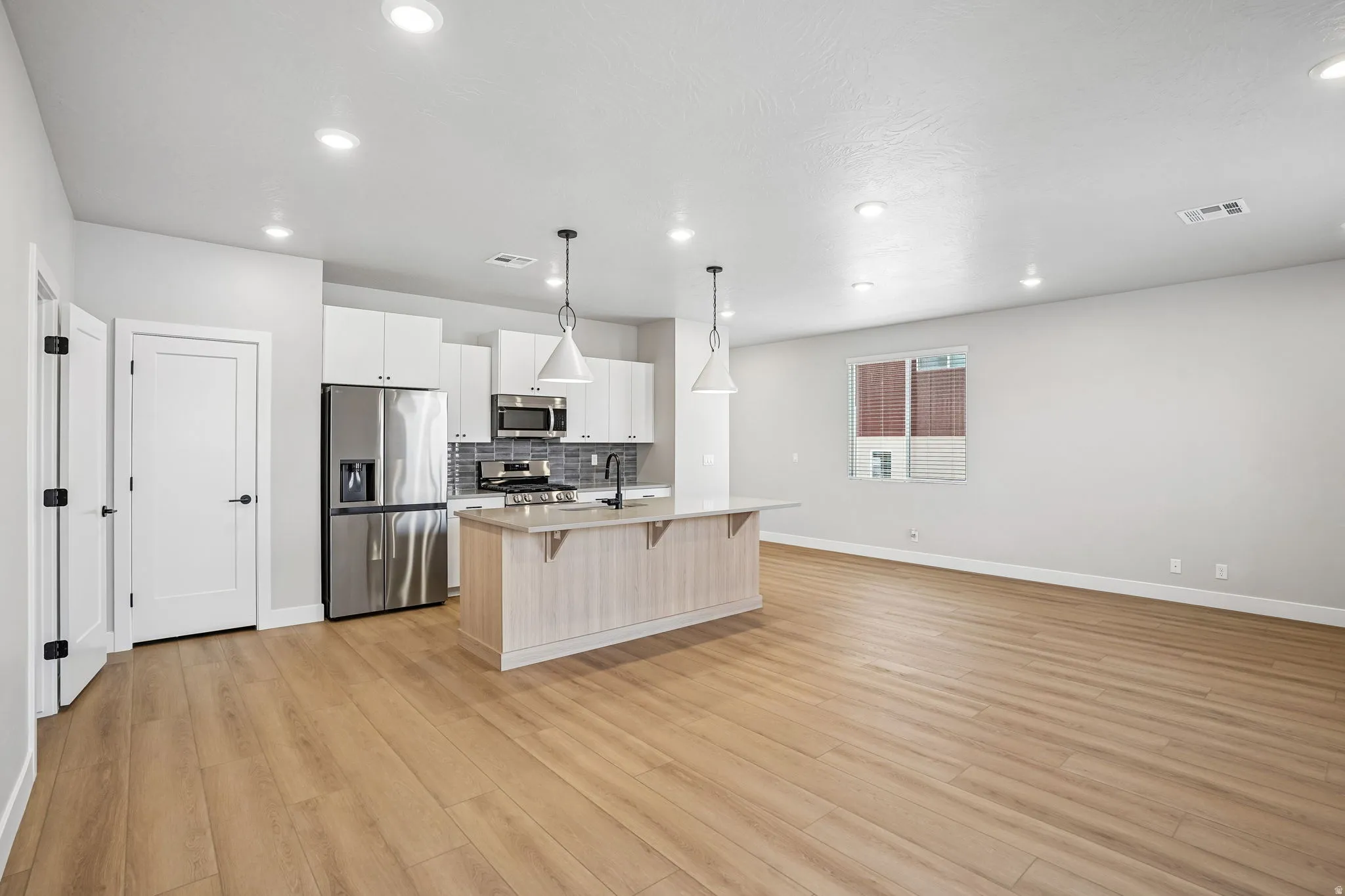 Open concept living area with wood-finish flooring, recessed lighting, and white walls