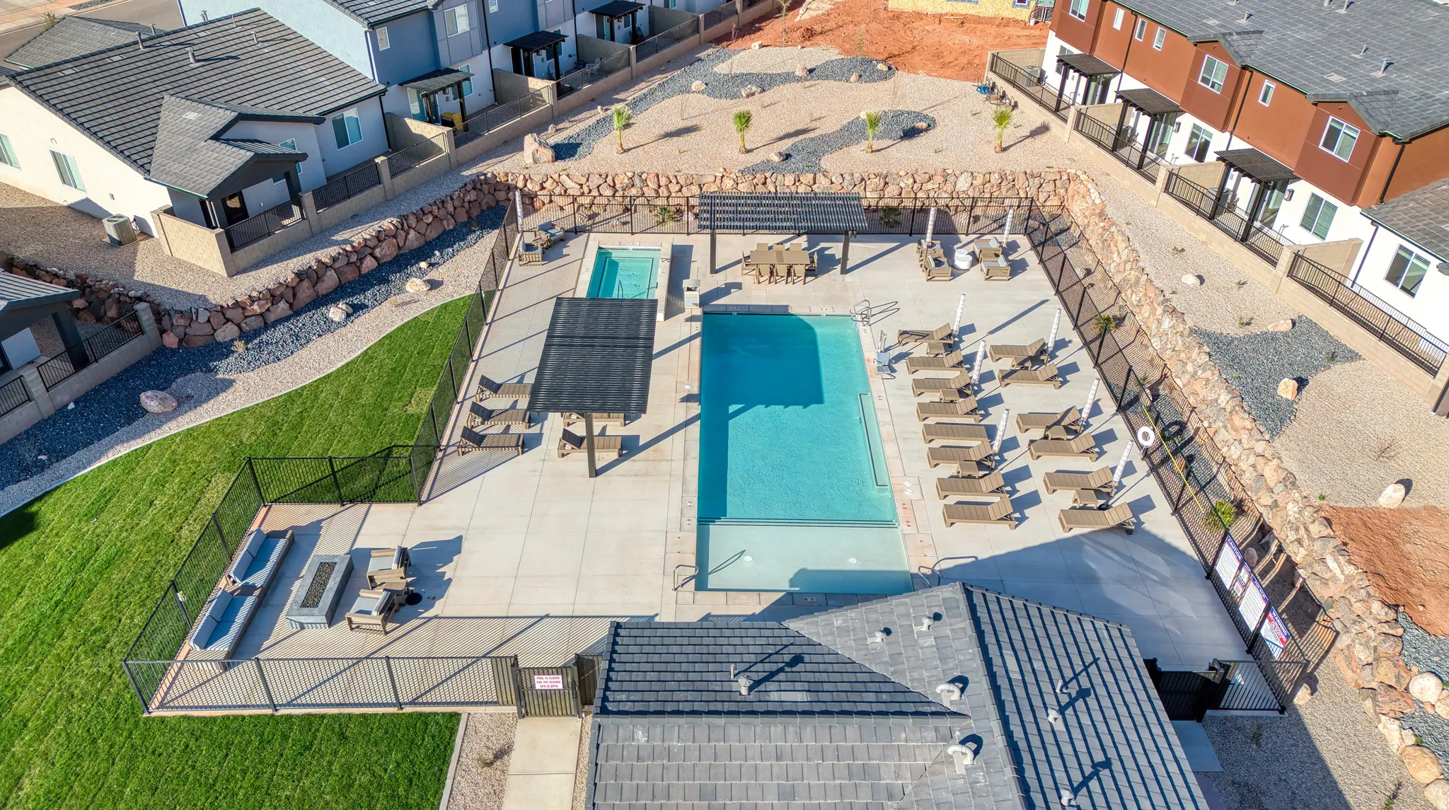 Resort-Style Outdoor Living Space Featuring Sparkling Swimming Pool, Expansive Hardscape Patio, Lounge Seating Areas, and Manicured Lawn with Residential Structures Surrounding the Retreat