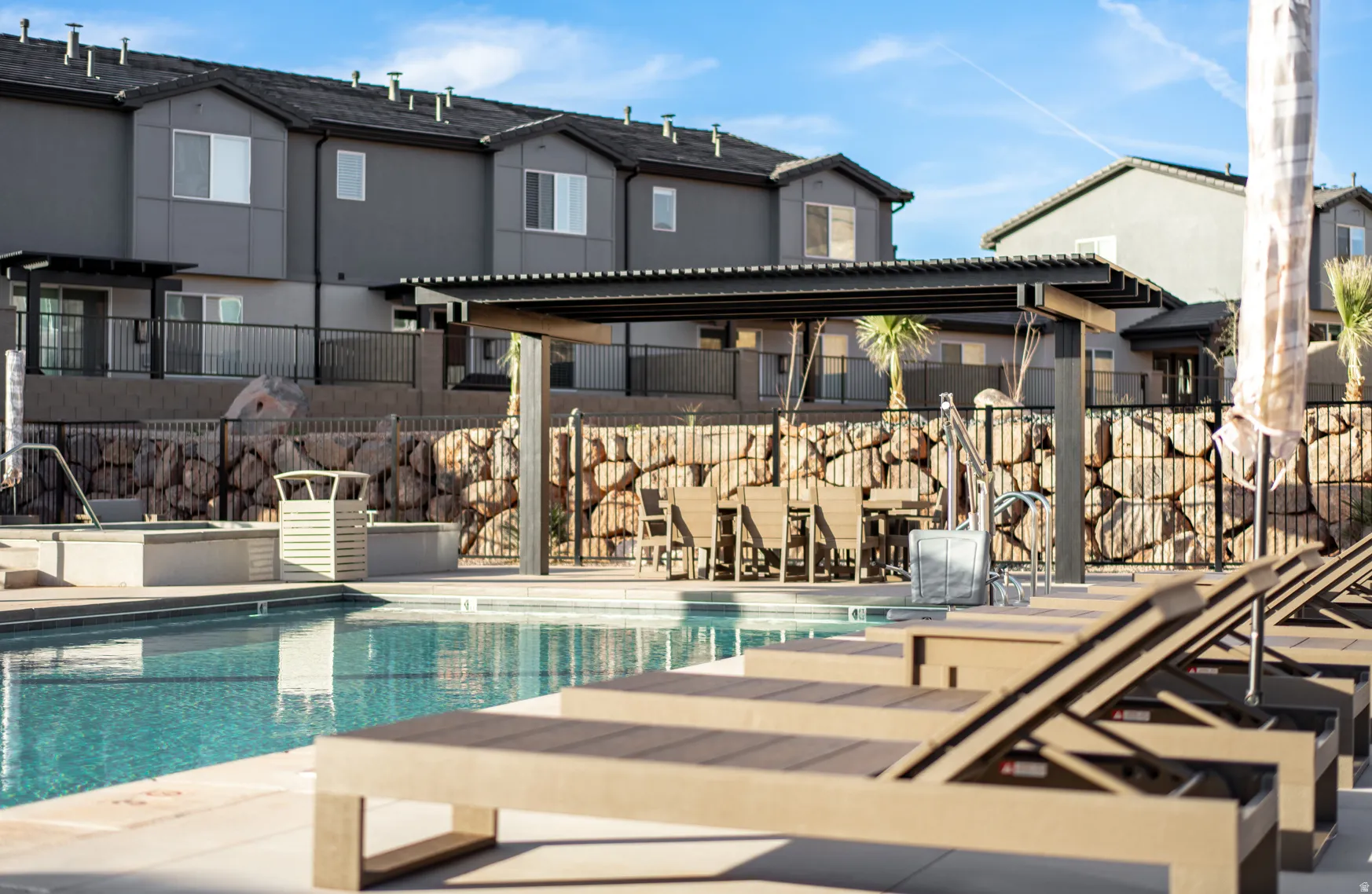Resort-style pool area featuring a large swimming pool, integrated spa, and an attached shaded pergola