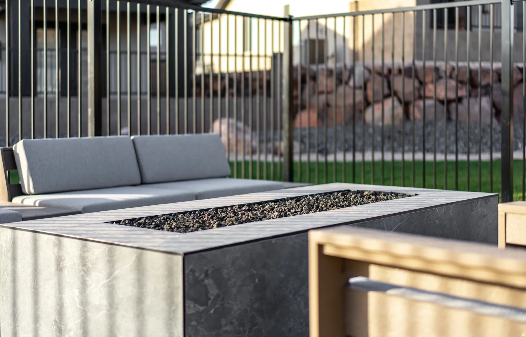 Outdoor fire pit with dark stone-finish surround, black fire media, and adjacent seating