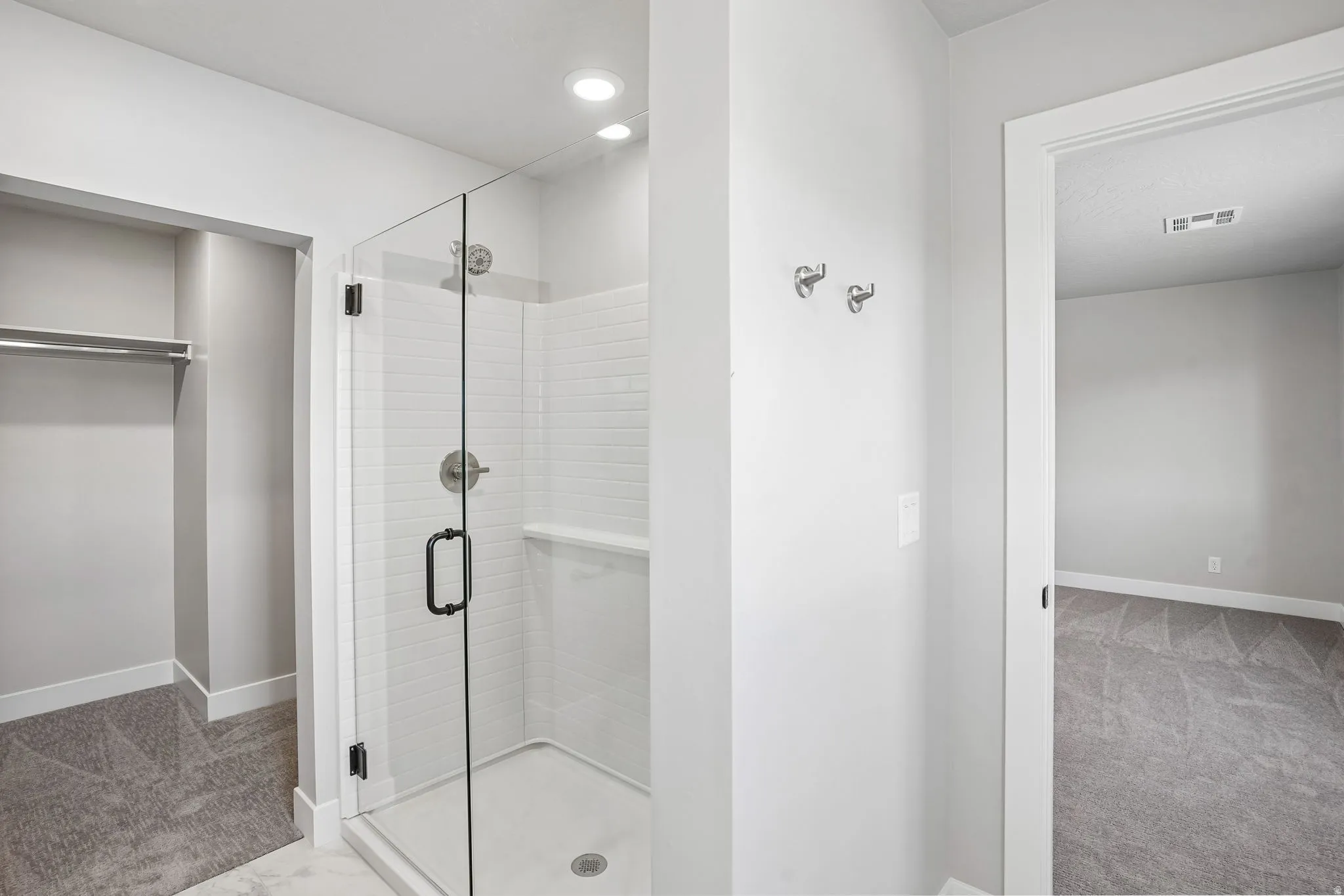 Glass-enclosed shower with subway tile surround, recessed lighting, and built-in shelving