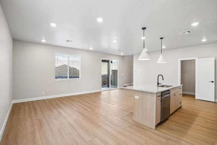 Kitchen island with integrated sink, stainless steel dishwasher, and pendant lighting