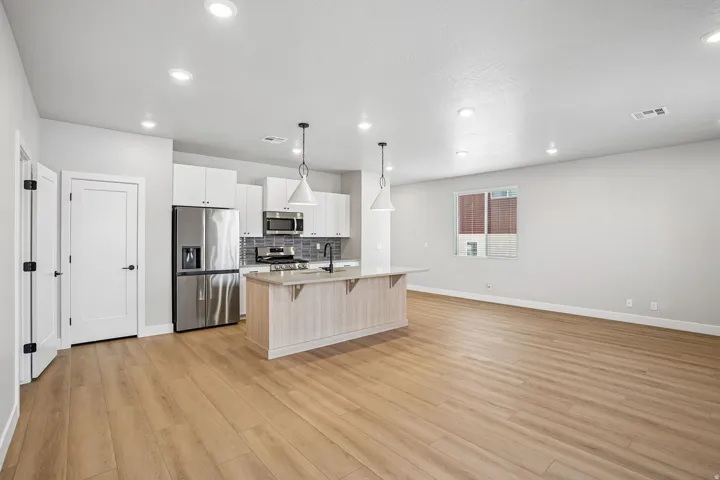 Open concept living area with wood-finish flooring, recessed lighting, and white walls
