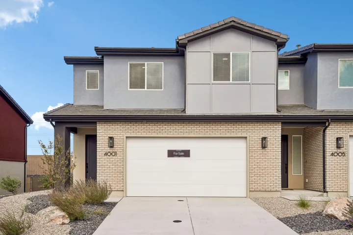 Contemporary exterior featuring light brick, gray siding, a two-car garage, and modern exterior lighting