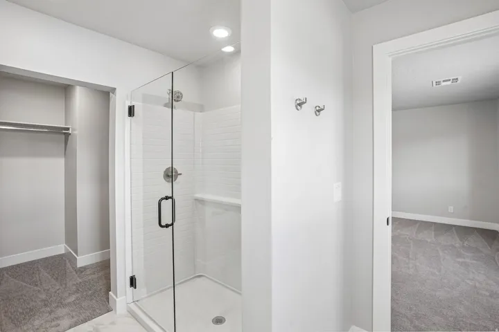 Glass-enclosed shower with subway tile surround, recessed lighting, and built-in shelving