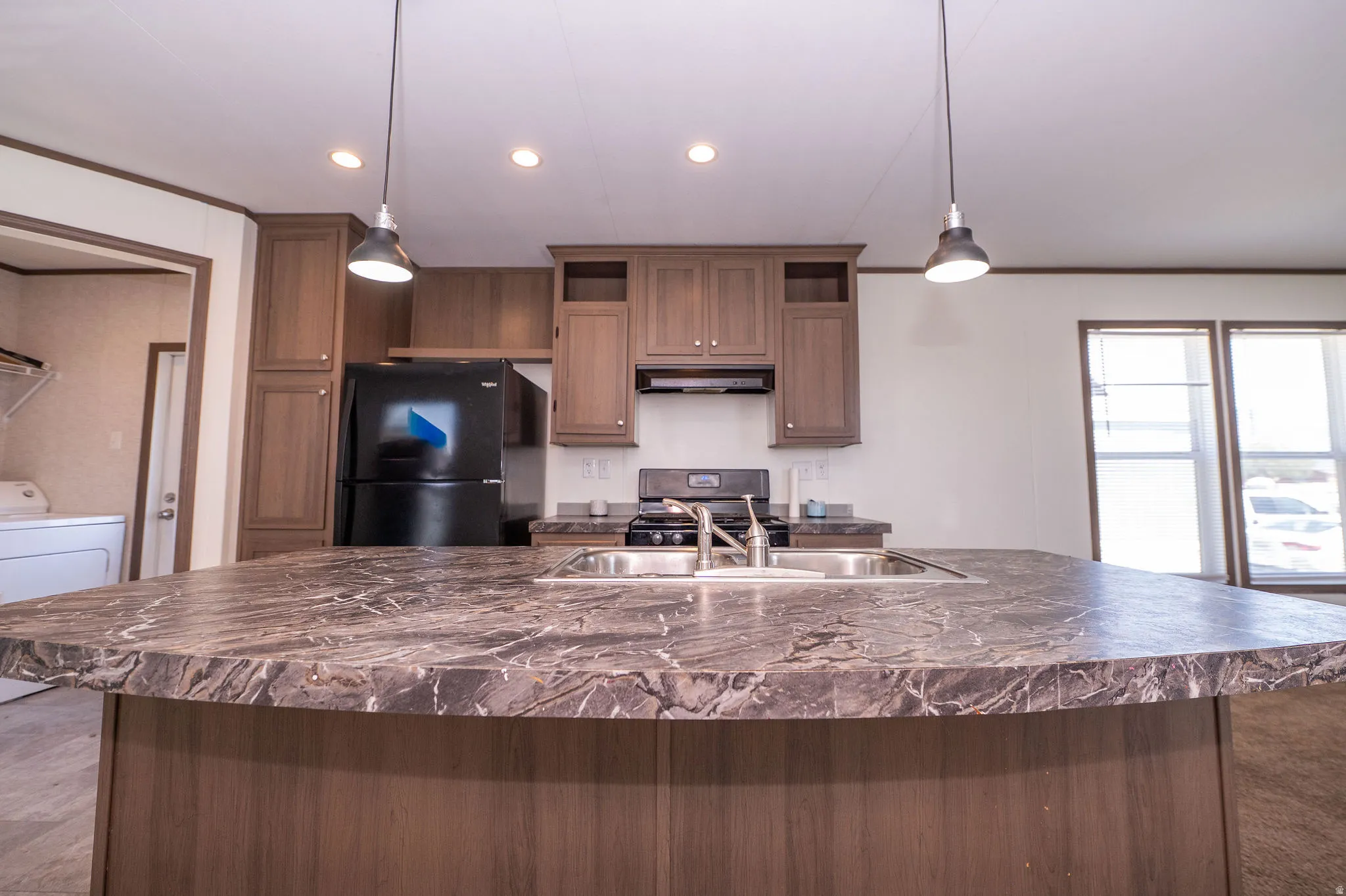 Kitchen island featuring a double basin sink and stone-look countertop