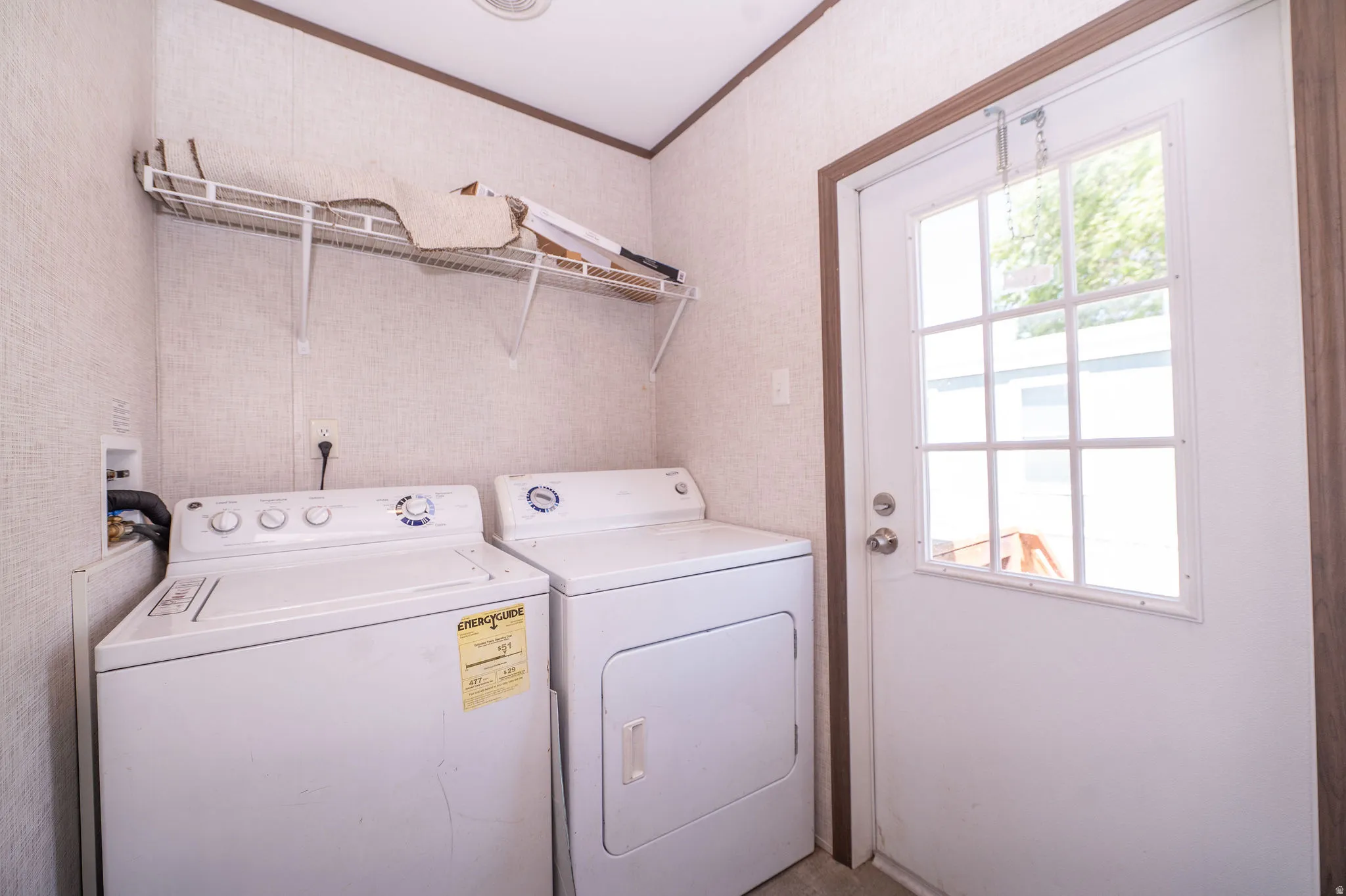 Dedicated laundry area featuring a washer and dryer, an overhead wire shelving unit, and a windowed exterior door