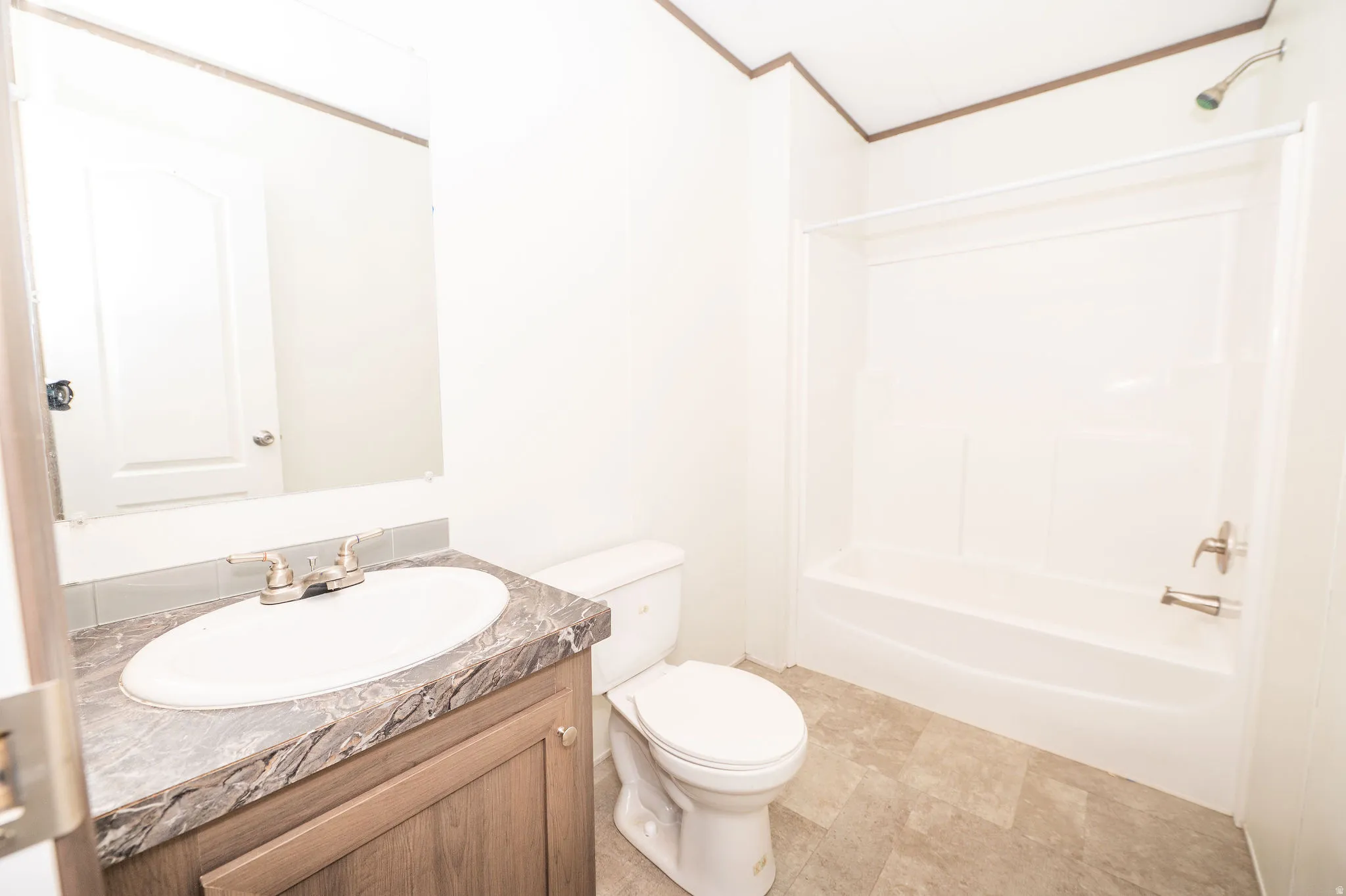 Bathroom featuring a wood-finish vanity with a stone-look countertop, an oval undermount sink, and a brushed nickel faucet