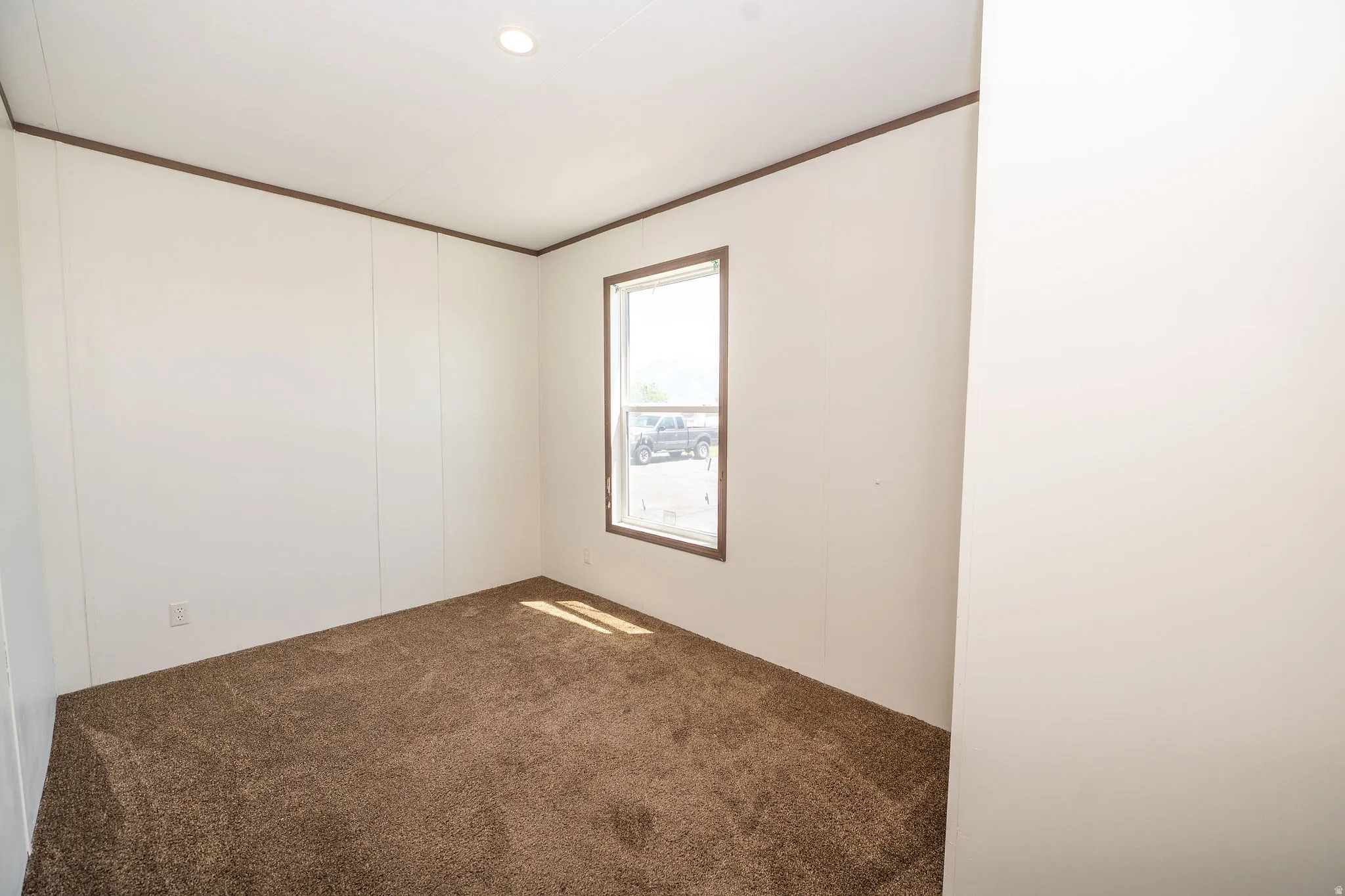 Carpeted interior space with a single window and recessed ceiling lighting
