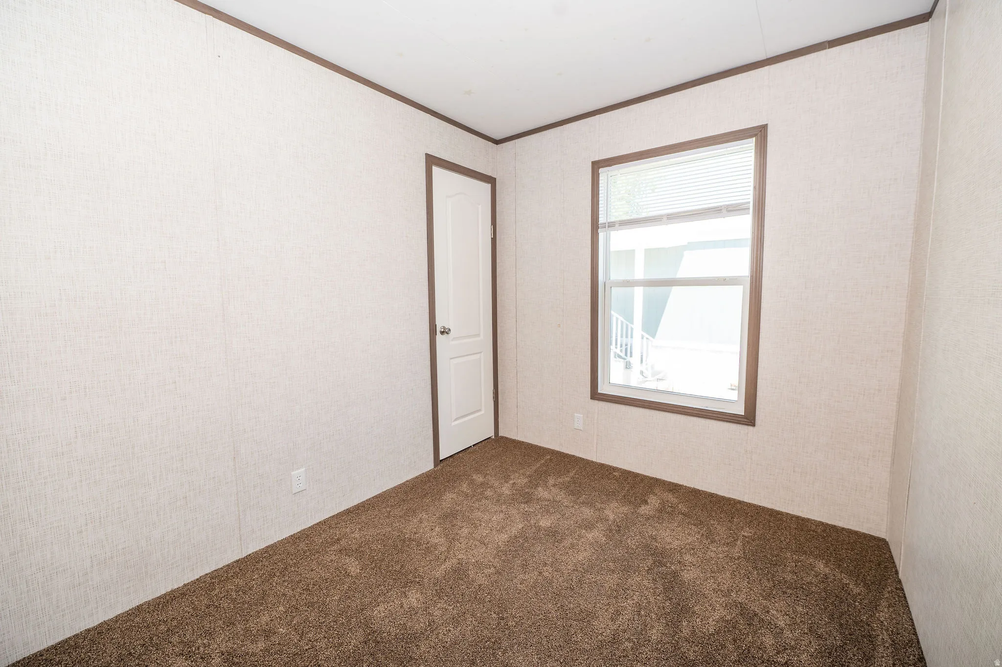 Neutral-toned walls featuring a textured finish, brown trim, and plush brown carpeting