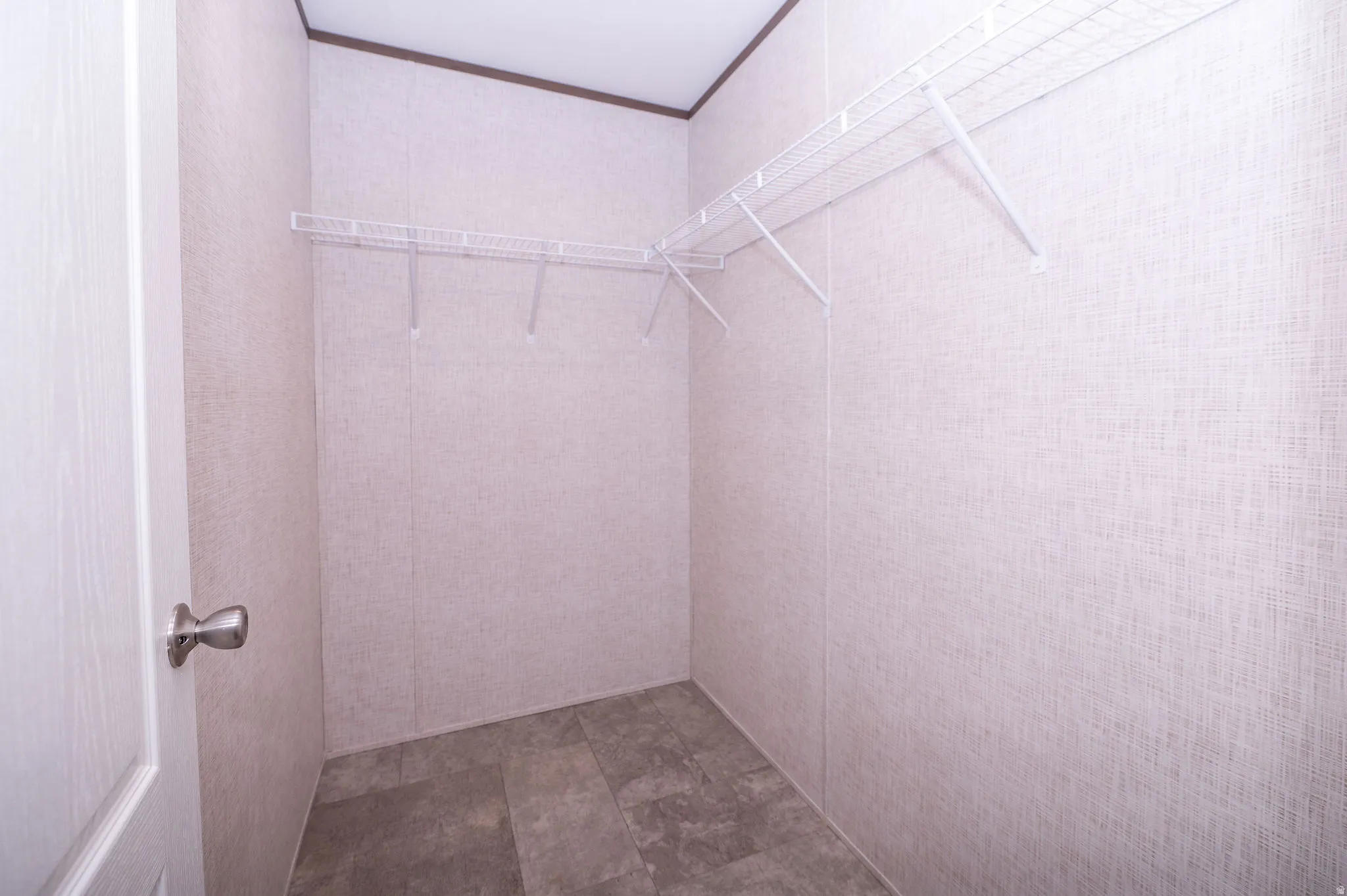 Walk-in closet with textured wall panels, wire shelving system, and wood-finish flooring