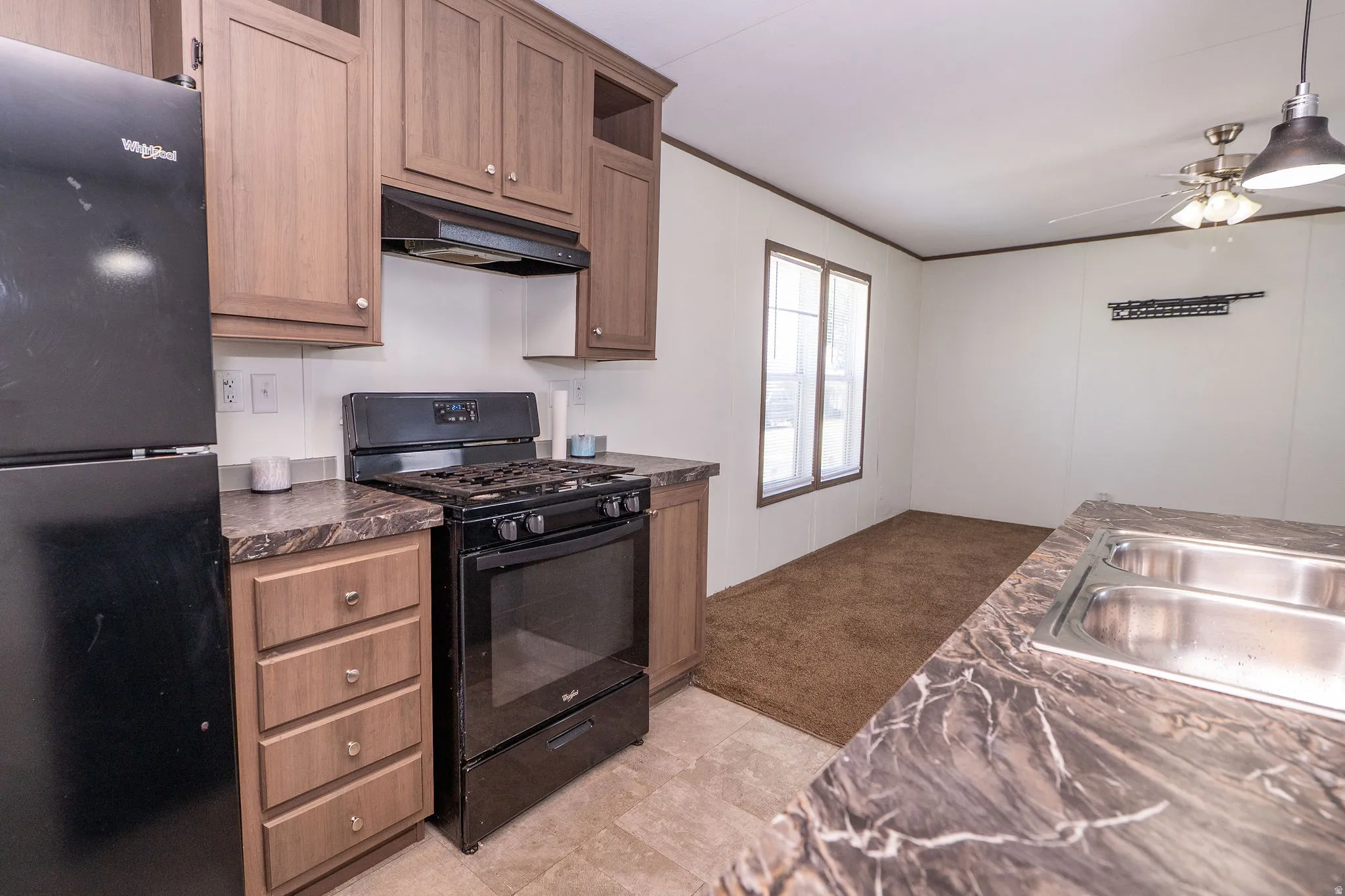 Kitchen featuring wood-finish cabinetry, dark countertops, and a stainless steel double-basin sink