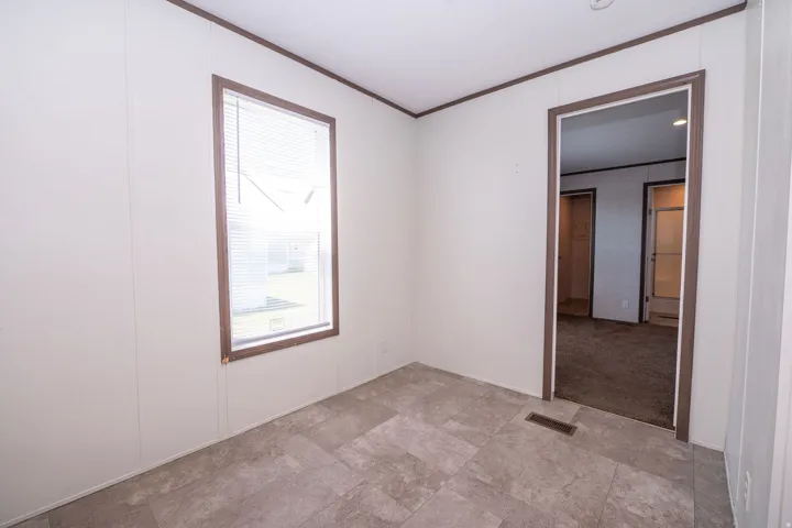 Room featuring light-toned walls, a single window with blinds, and brown trim
