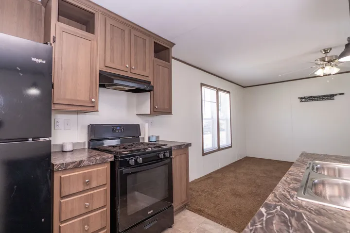 Kitchen featuring wood-finish cabinetry, black appliances, patterned countertops, and a double basin sink