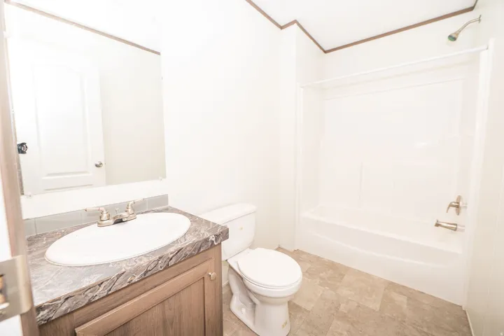 Bathroom featuring a wood-finish vanity with a stone-look countertop, an oval undermount sink, and a brushed nickel faucet