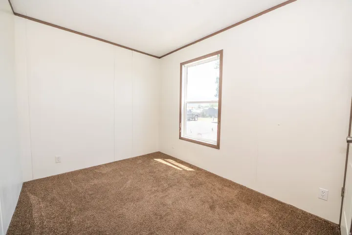 Room featuring soft brown carpet, white wall panels, and contrasting brown trim