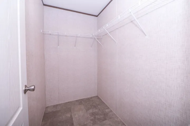 Walk-in closet with textured wall panels, wire shelving system, and wood-finish flooring