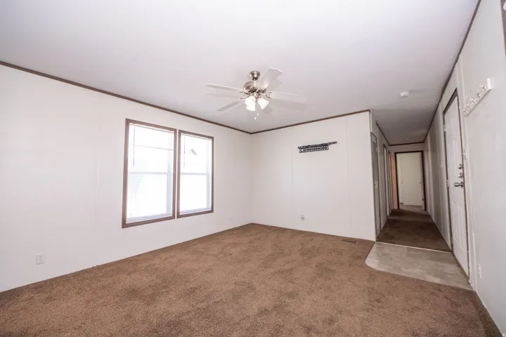 Spacious living area featuring brown carpeting, white paneled walls, and dark trim