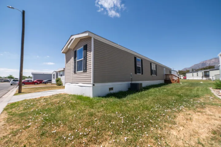 Single-level residence featuring tan horizontal siding, white trim, and dark window shutters