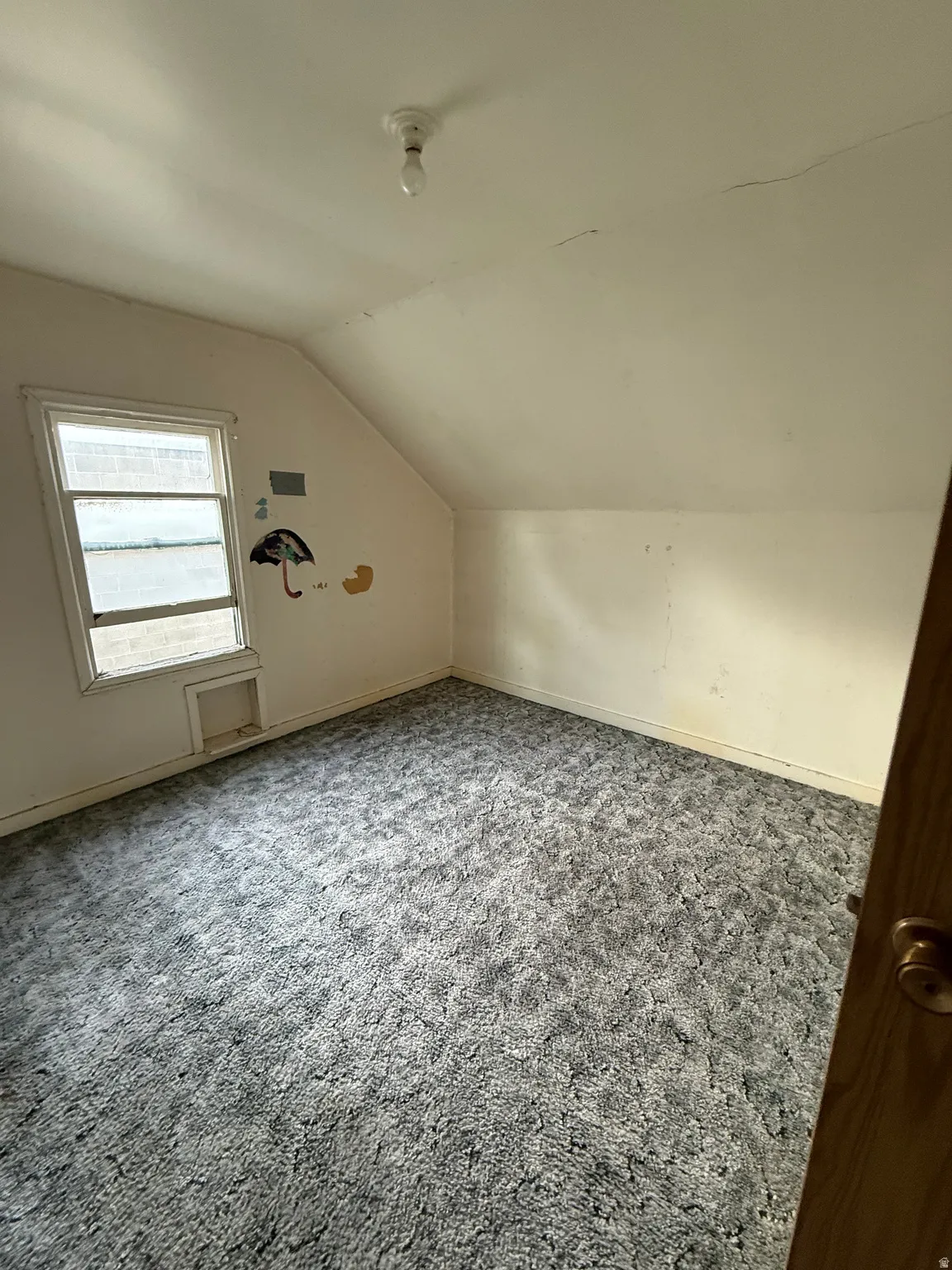Room featuring a window, sloped ceiling, and textured carpet flooring