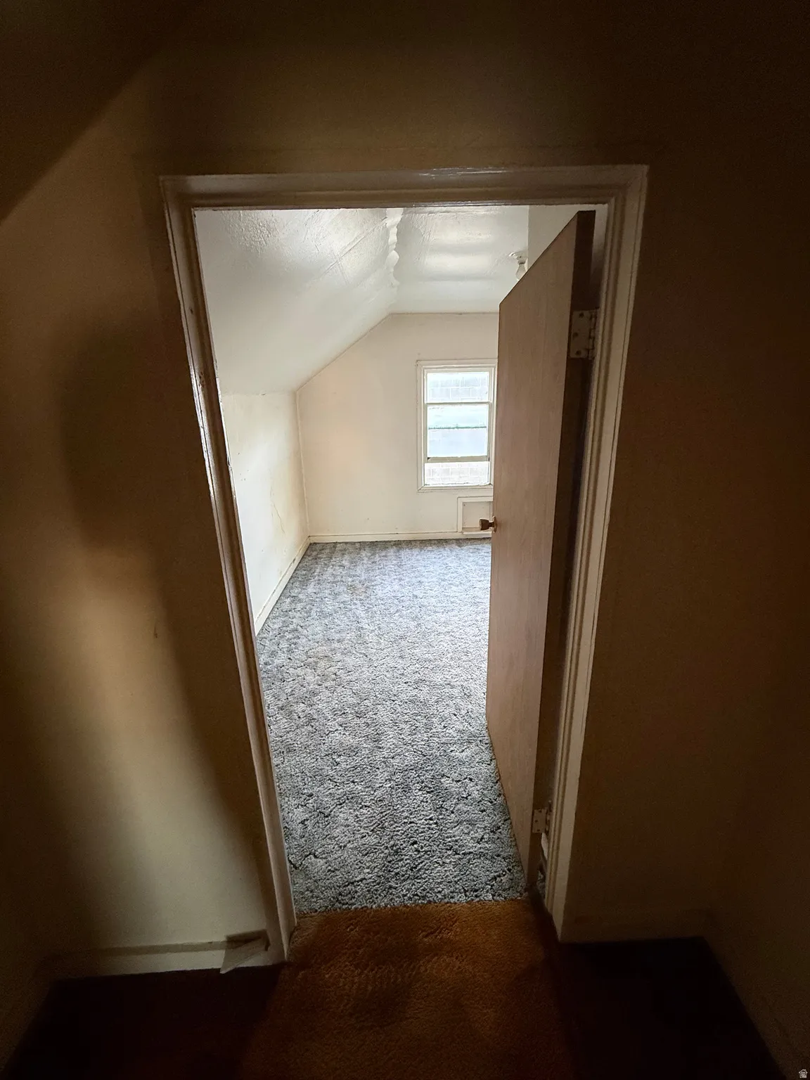 Room with sloped ceilings, a single window, and light-colored walls