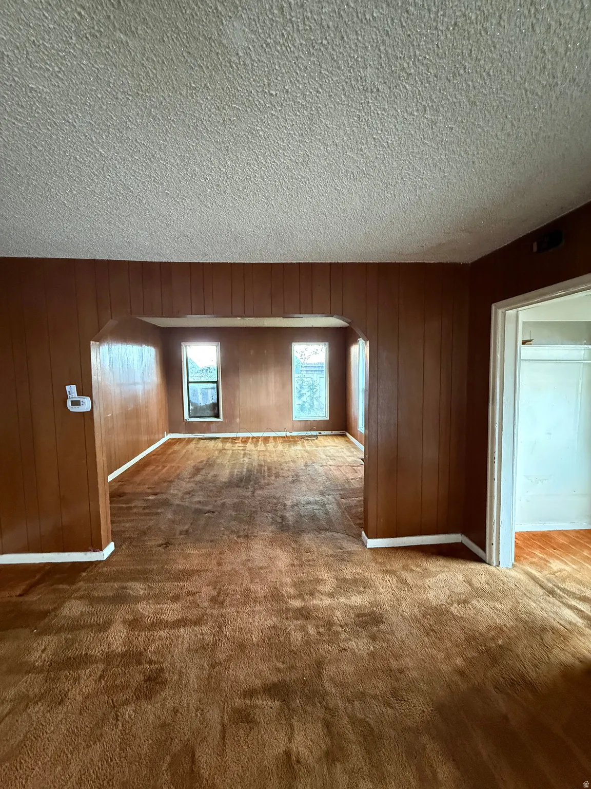 Interior space featuring wood-paneled walls and a popcorn ceiling