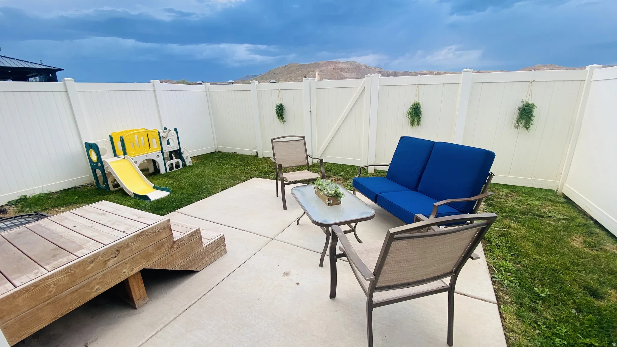 Private backyard with a concrete patio, wood deck, and white vinyl fencing