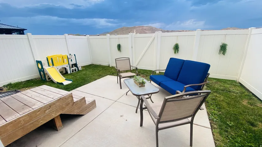 Private backyard with a concrete patio, wood deck, and white vinyl fencing