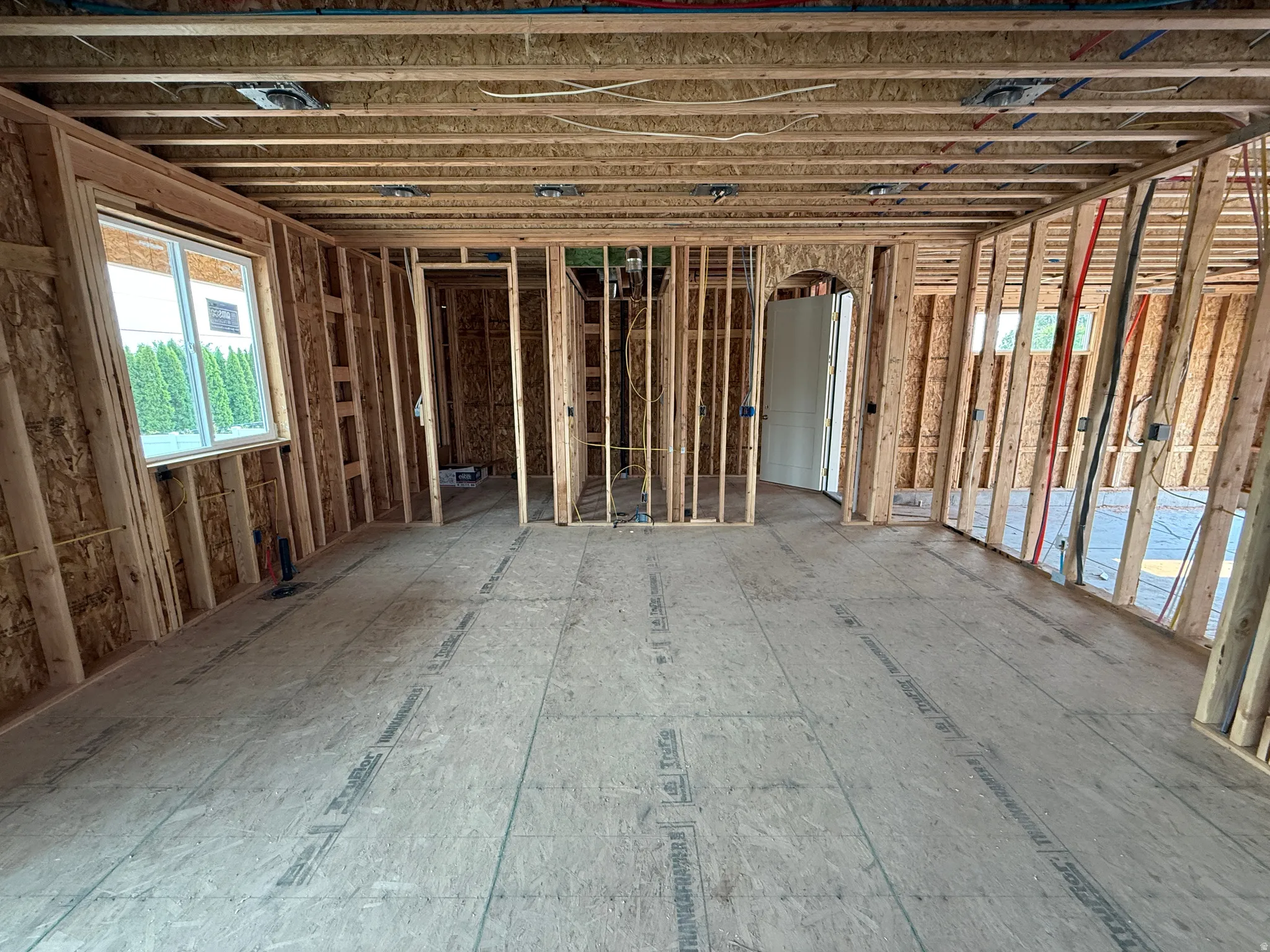 Interior framing showcasing structural elements, plywood subflooring, and a visible window opening
