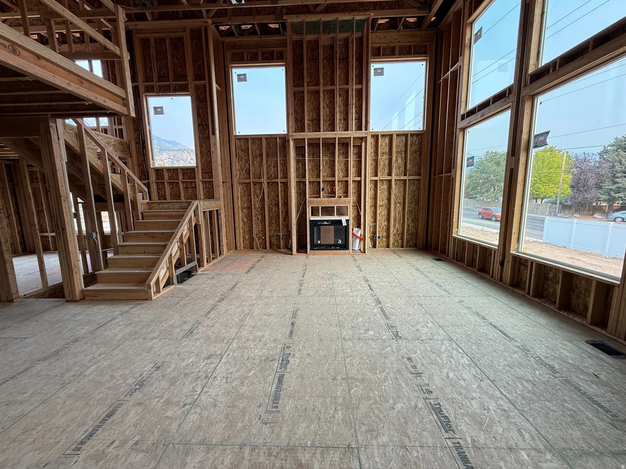 Open-concept interior featuring a prominent two-story framing structure, a built-in fireplace unit, and a grand staircase with an open railing design