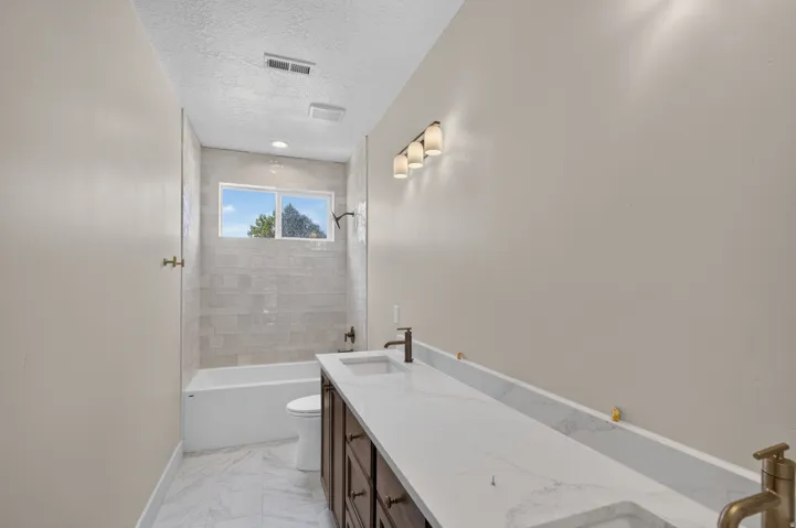 Dual sink vanity with dark wood-finish cabinetry, white countertop, and contemporary bronze fixtures