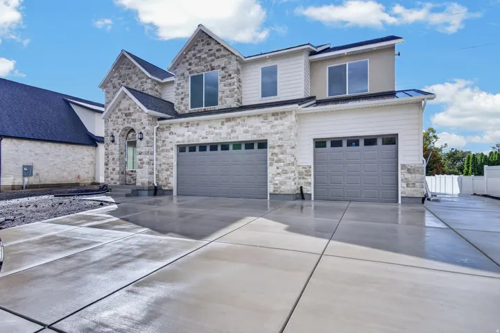 Stone and siding exterior with multiple pitched roofs, a two-car garage, an additional single-car garage, and a concrete driveway